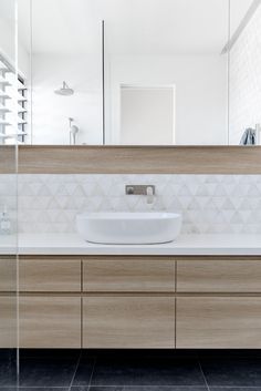 a white sink sitting under a large mirror next to a wooden cabinet and counter top