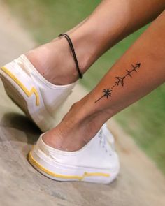 a woman's foot with a small tattoo on her left ankle and palm tree in the middle