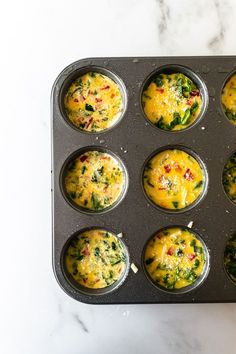 muffin tins filled with eggs and spinach on a marble countertop top