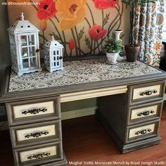 an old desk with flowers painted on the wall behind it and a small white lantern