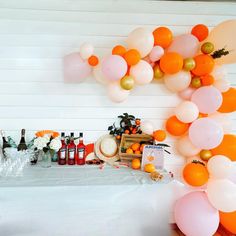 an orange and white party with balloons, confetti and bottles on the table