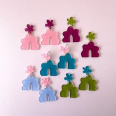 several different colored wooden earrings with flowers on them, all in the shape of people