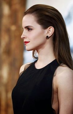 a woman with long brown hair wearing black dress and red lipstick on her lips is looking at the camera