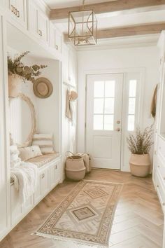 a hallway with white walls and wooden floors, an area rug on the floor and potted plants