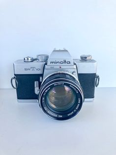 an old camera sitting on top of a white table next to a black and silver object