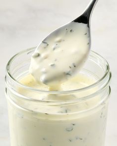 a spoon full of yogurt sitting on top of a jar filled with liquid