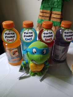 a table topped with bottles of juice next to a stuffed animal and an orange turtle