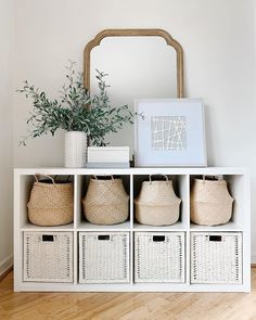 a white shelf with baskets and plants on top