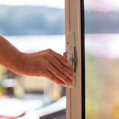 a person's hand on the handle of a door with a window in the background