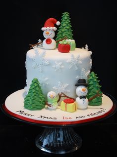 a christmas cake decorated with snowmen, trees and santa hats on a black background