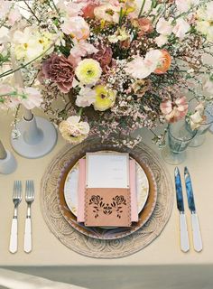 a table set with plates, silverware and flowers