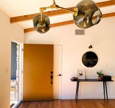 two lamps hanging from the ceiling above a table with a mirror on it and a door in the background