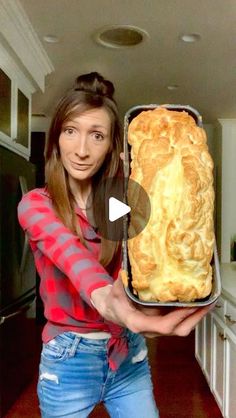 a woman holding up a large loaf of bread