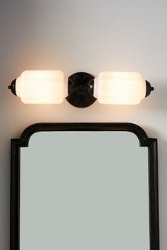 a bathroom vanity with two lights and a mirror on the wall next to each other