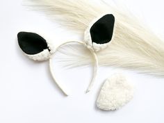 a white and black cat ears headband on top of a white table next to a furry tail