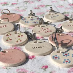 six ceramic key chains with different designs on them sitting on a table covered in pink and blue flowers