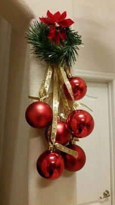 a bunch of red ornaments hanging on the wall next to a white door with gold ribbon