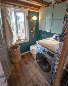 a washer and dryer in a small room with wood flooring on the walls