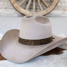 The Brown Snake Print hat band is a stylish leather accessory featuring a warm brown and black colored print on genuine leather. It measures 22.5" long and 1" wide. Adjustable leather ties ensure a perfect fit for almost any hat.     Length: 22.5 inches  Width: 1 inch  Adjustable Leather ties  Genuine Leather  *Hat not included*  CA Residents: Prop 65 Warning ↗️ Lv Hat Band, Luxury Adjustable Country Hat Band, Cheap Classic Hat Band For Spring, Silver Hats, Beaded Hat Bands, Brown Snake, Kids Belt, Beaded Hat, Leather Hat