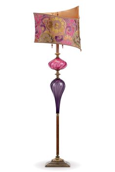 a lamp that is on top of a stand with a pink and purple shade over it