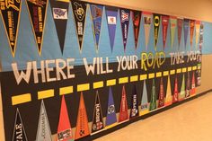 a bulletin board with flags and words on it in a school hallway that says where will your road take you?