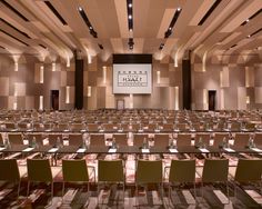 an empty conference room with rows of tables and chairs in front of a projector screen