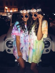 two young women standing next to each other in front of a car