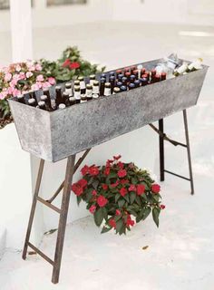 an outdoor table with flowers and bottles on it in front of a white building,