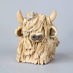 a close up of a toy cow with long hair and flowers on it's head