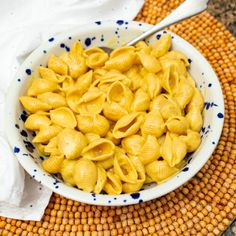 a white bowl filled with macaroni and cheese on top of a woven place mat