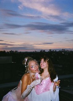 two beautiful young women standing next to each other in front of a cityscape