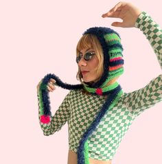 a woman wearing a knitted hat and scarf holding her hands up to the side