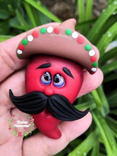 a hand holding a red toy with a mustache