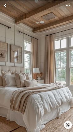 a large white bed sitting in a bedroom next to two windows