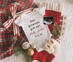 a baby's first christmas gift is on the bed next to other holiday items