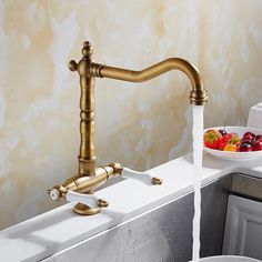 a faucet that is sitting on top of a sink next to a bowl of fruit