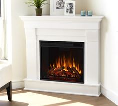 a white fireplace with a fire in it and pictures on the top shelf next to it