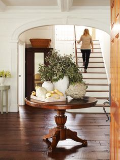 a woman is walking up the stairs in her home with vegetables and bread on the table