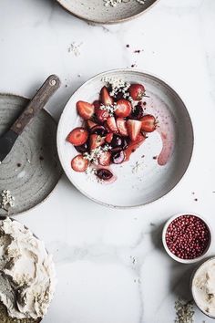 a plate with strawberries and berries on it next to bowls of whipped toppings