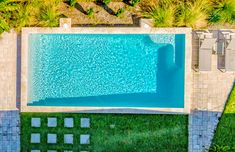 an aerial view of a swimming pool in the middle of a yard with grass and trees