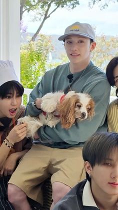 a group of young people sitting next to each other on a porch holding small dogs