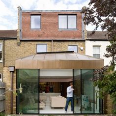 a man standing in front of a house with glass walls and doors on the outside