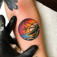 a person with a tattoo on their arm that has a sunset and palm trees in it