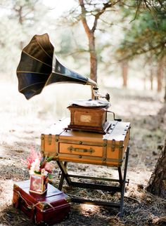 an old fashioned record player sitting on top of a table next to a trunk and umbrella