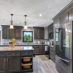 a large kitchen with granite counter tops and stainless steel appliances, along with dark wood cabinets