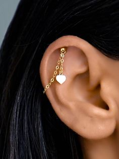 a close up of a person's ear wearing a gold chain and heart earrings