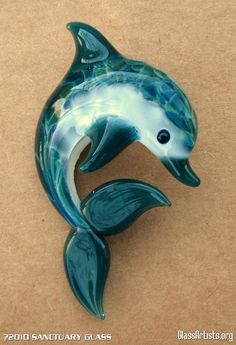 a blue and white dolphin figurine sitting on top of a brown surface with its mouth open