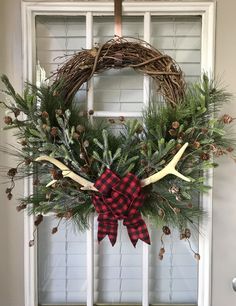 a wreath with antlers and pine cones hangs on the front door