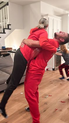 a man and woman are dancing in the living room with their arms around each other