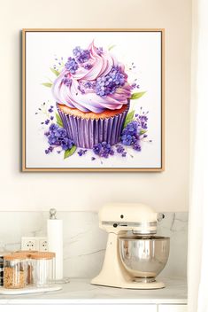 a cupcake with pink frosting and purple flowers on it next to a mixer